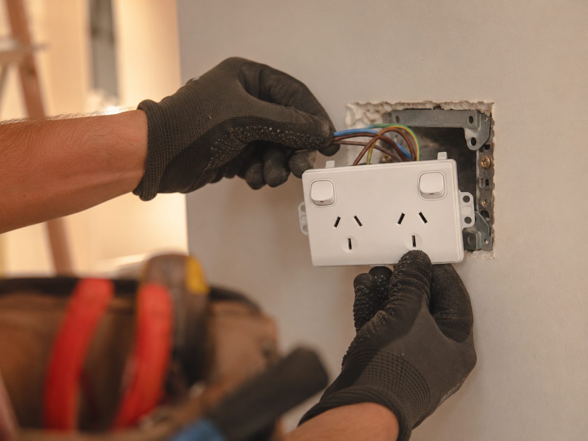 Gloved hands wiring an Australian power point